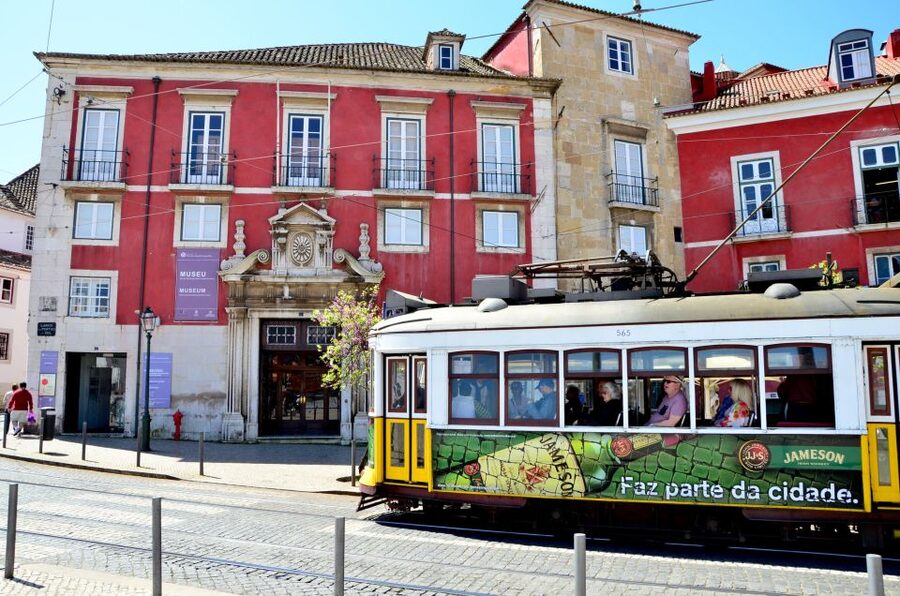 A yellow tram climbing a tiled street in Lisbon